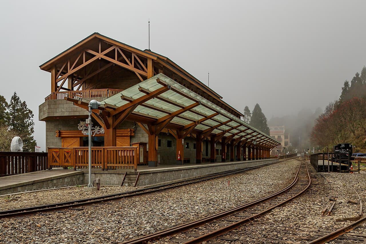 A red Alishan Forest Railway train through the mountain forest.